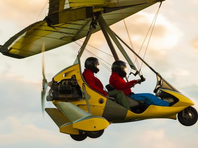 Microlight aircraft in the air flying in sunset