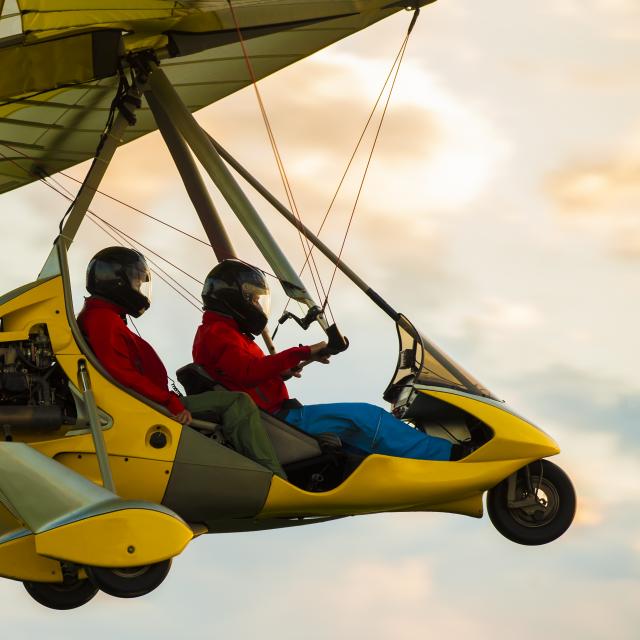 Microlight aircraft in the air flying in sunset