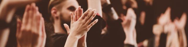 Group of people clapping hands in the theater, close up of hands. Dark tone.