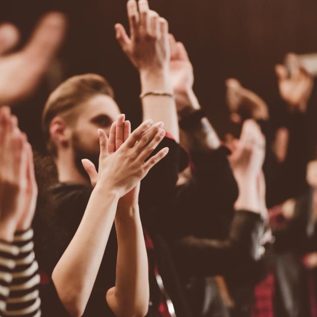 Group of people clapping hands in the theater, close up of hands. Dark tone.