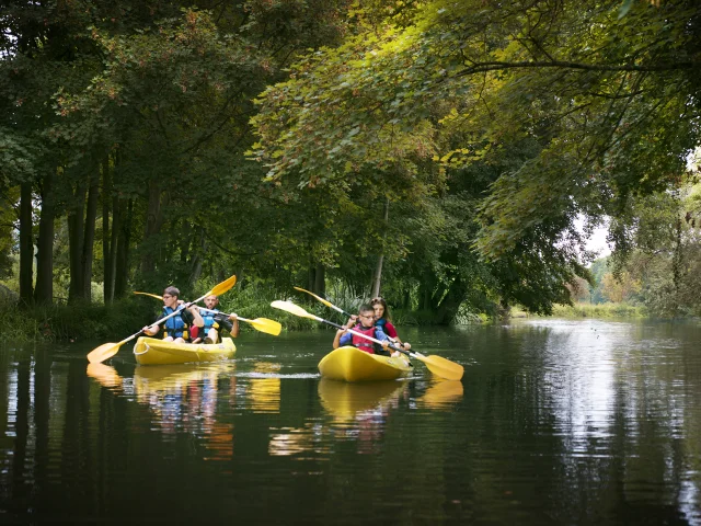 Une famille pagaye en canoë sur la rivière de l'Eure sous les arbres verts