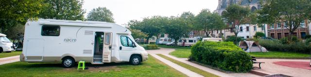 photo d'une aire de camping car surplombée par l'église de pont de l'arche