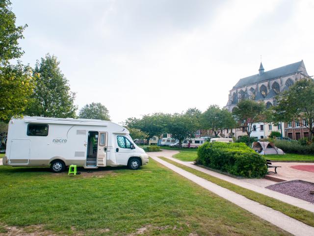 photo d'une aire de camping car surplombée par l'église de pont de l'arche