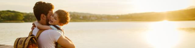 Photo of a young man and his son spending some quality time together while sitting on a lake dock