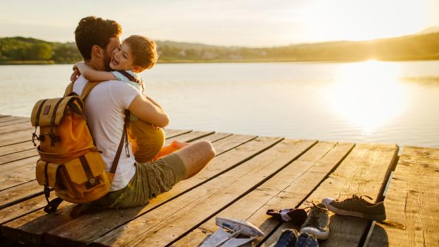 Photo of a young man and his son spending some quality time together while sitting on a lake dock