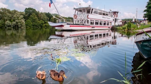 photo d'un bateau blanc en bord de seine avec nénuphars et canards en Normandie