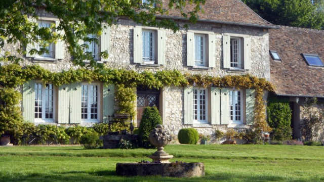 Grande maison en pierre avec végétation sur les murs de la ferme des ruelles