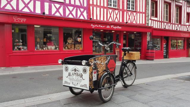 Un tricycle garé devant la devanture d'une boutique à colombage rouge à Louviers dans l'Eure