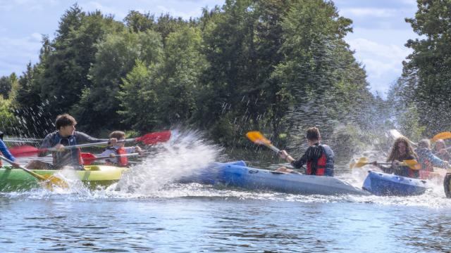 Des jeunes s'arrosent avec leur pagaie en canoë kayak sur la rivière de l'Eure